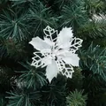 Sparkling white poinsettia flower ornament with glitter on green Christmas tree branch - White