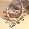 Detalle del collar de doble capa de perlas y cadena plateada con colgantes corazón - Plateado