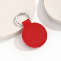 Detail view of red circular PU leather keychain with silver metal ring on a beige stand - Round / Red