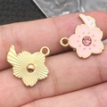 Pink enamel cherry blossom and gold flower charms with wing detail shown on fingertip - 1Pc Pink Rhinestone Cherry Blossom Wing 20x18mm