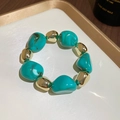 Detail of turquoise and gold beads bracelet on a white tray with golden frame - Bracelet / Green