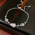 Makroaufnahme eines silbernen Armbands mit Perlen und funkelnden Herz-Elementen - Armband-Silber-Rosa