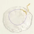 Detail of light purple beaded bracelet with gold lobster clasp on artistic background - Purple