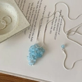 Detail of silver necklace with light blue grape pendant on an artistic book background - Necklace-Blue