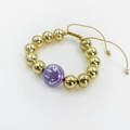 Macro detail of gold beaded adjustable bracelet with purple smiley face charm feature - Purple