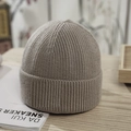 Close-up of light grey ribbed knit beanie on a wooden table with lifestyle decor - One Size / Light Gray