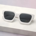 Detailed view of white thick-frame square sunglasses with dark gray lenses on a white stand - White Frame Gray Lens