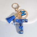 Blue resin letter T keychain with gold flakes, tassel, and butterfly charm - Letter T