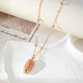 Gold-plated beach shell pendant necklace with orange dotted texture on a white shell tray - Orange Dotted Shell