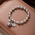 Macro view of silver-plated beaded bracelet with lotus leaf and bell charms on leather - Fortune