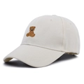 Dettaglio del cappellino in cotone crema con ricamo a orsetto marrone e trama in saia - Taglia unica / Beige