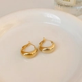 Detailopname van goud vergulde druppel oorbellen op een wit keramisch bordje - Goud Rond (Silver Earring Post)