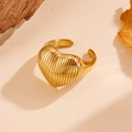 Vista detallada de un anillo de corazón dorado con textura de rayas verticales en fondo - Dorado
