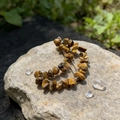 Macro shot of tiger eye stone moon hair clip on a natural rock with garden background - Tiger's Eye