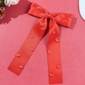 Détail du nœud papillon en satin rouge avec motifs de cœurs et longs rubans - Rouge
