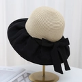 Detail of elegant black wide-brim sun hat with straw crown and bow knot on gold stand - Black