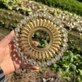 Detailed view of round gold metal wall decor with sparkling crystals and radial textures - Gold Iridescent White