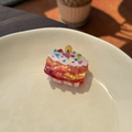 Close-up of creative acrylic cake flower hair clip with candle detail on a ceramic plate - Flame Cream - Cake Candle Small Claw
