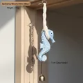 Carillon hippocampe bleu clair avec cloche dorée et cordon tressé sur bois clair - Bleu