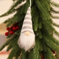 Close-up of a knitted Christmas gnome ornament hanging on a pine tree with berries - Knitted Hanging Grey Style B