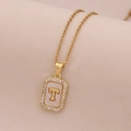 Vue macro du collier doré 18K avec pendentif lettre T, nacre et petits cristaux - Lettre T