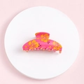Top view of pink hair claw clip with orange flower patterns on white circular base - Pink Orange Flower