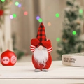 Close-up detail of a cute Christmas gnome covering eyes wearing a red buffalo plaid hat - Red