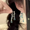 Détail de boucles d'oreilles argentées avec perles de verre bleues portées par un mannequin - Style de gland goutte d'eau bleue multicouche argentée