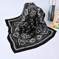 Detail of a black square silk scarf with white paisley patterns on a stylish background - Black Paisley