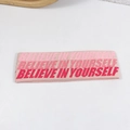 Pink knitted yoga headband featuring white Believe In Yourself text on a clean background - Pink