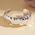 Dettaglio del bracciale a polsino in argento con trama in metallo liquido e riflessi - Argento