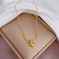 Close-up of golden teardrop pendant on a sleek snake chain over white silk fabric - Titanium Steel / Gold (K105)