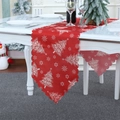 Close-up of red Christmas table runner with white trees and wavy edges on a festive table - Christmas Tree