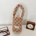 Dettaglio del portabicchiere in peluche beige a pois rossi con etichetta laterale - Beige con cuore rosso