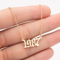 Macro view of gold stainless steel necklace with 1987 birth year pendant in retro font - Black Paris 1987 / Gold