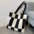 Detail der schwarz-weiß karierten Canvas-Tasche mit schwarzen Riemen im Wohnambiente - Rechteckiges Gitter-Schwarz