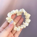 Elegant cream silk satin hair scrunchie held in hand with soft glossy texture finish - Creamy White