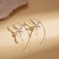 Detail of silver iris flower earrings with long hooks on a minimalist textured stone background - Silver