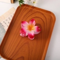 Pink and white gradient plumeria hair claw clip with yellow center on wood tray - Gradient Red