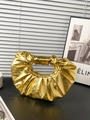 Vista detallada del bolso plisado dorado metalizado sobre una superficie de madera oscura - Dorado