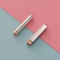 Detailed view of silver and rose gold cylindrical and rectangular metal urn pendants - Cylinder / Rose Gold (Inner) + Steel (Outer)