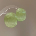 Macro detail of light green translucent resin earrings with a brushed texture finish - Olive Green