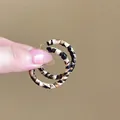 Close-up of leopard print oversized hoop earrings with golden metal studs and texture - 25# Hoop - Round/Small