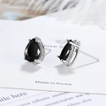 Elegant pear cut black zircon stud earrings in silver prong setting on white display card - Black Zirconia