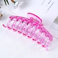 Close-up of large pink translucent hair claw clip with metal spring on a floral background - Jelly Transparent Purple