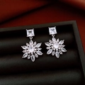 Detailed close-up of 14k gold plated snowflake drop earrings with clear zircon stones - Silver