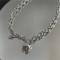 Détail macro du collier chaîne en acier argenté avec pendentifs dent et étoile - Style Pendentif Dent Étoile Argent