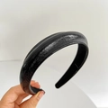 Close-up of black leather sponge headband showing soft texture and premium glossy finish - Black