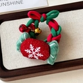 Detail eines festlichen Weihnachts-Haargummis mit Glöckchen und plüschigem Schneeflocken-Anhänger - Süßigkeit