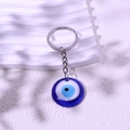 Blauer Evil Eye Schlüsselanhänger mit silbernem Metallring auf weißem Hintergrund - Blau